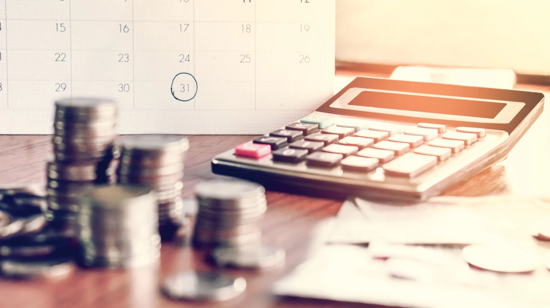 Image d'un calendrier, calculatrice et monnaie.