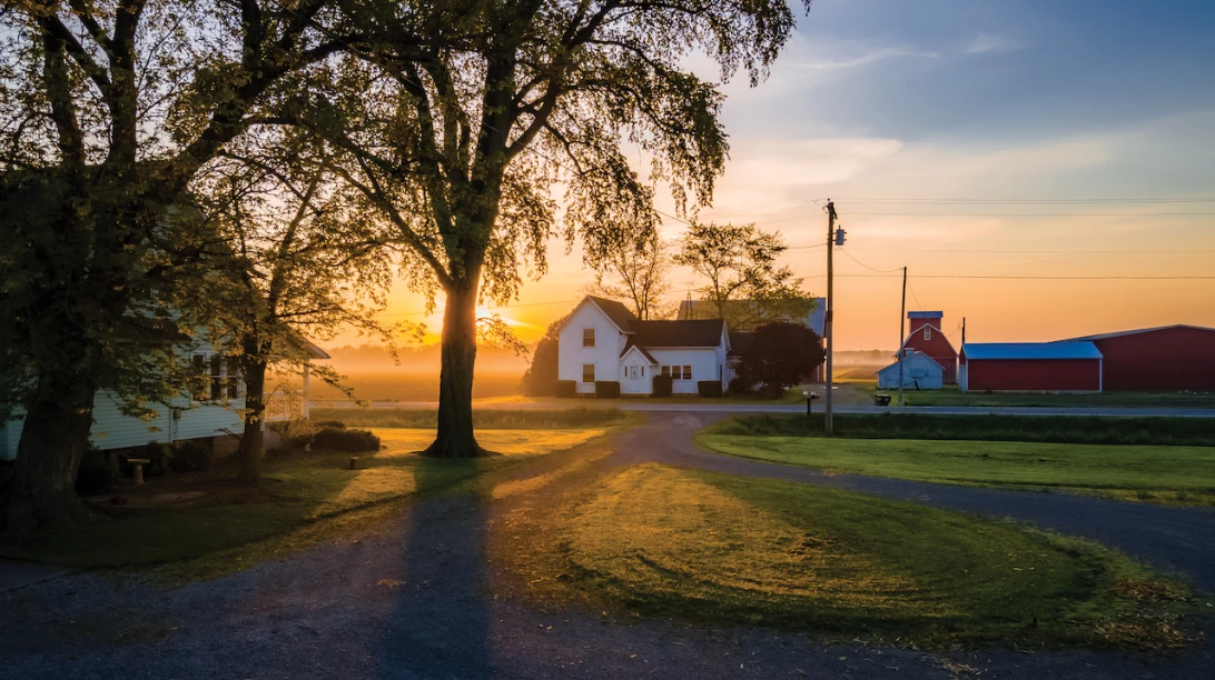 Maison sur une terre agricole, sur fond de coucher de soleil