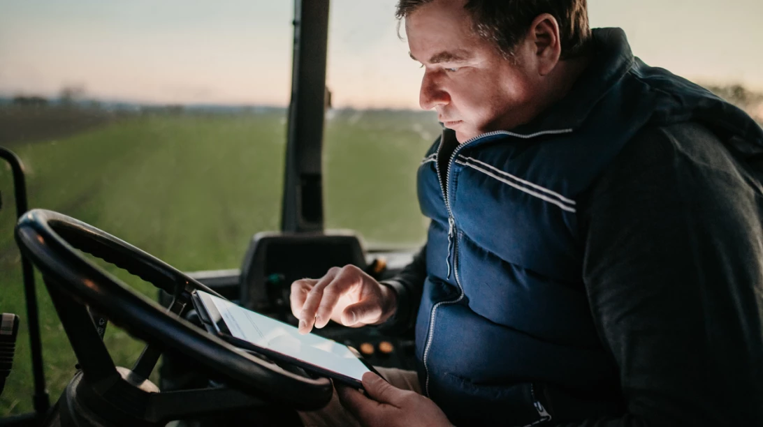 Homme dans un tracteur regardant sa tablette.