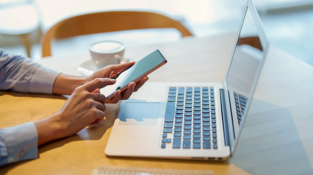 Personne utilisant son téléphone et son ordinateur.