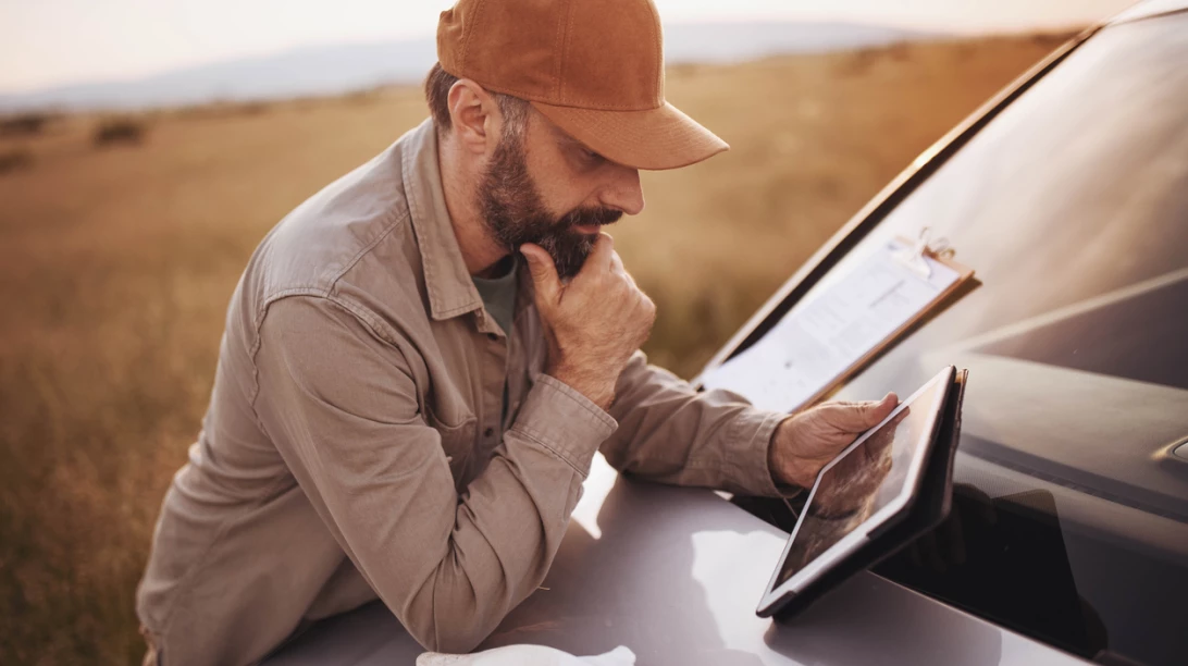 Homme observant sa tablette sur le pare-choc d'un camion.