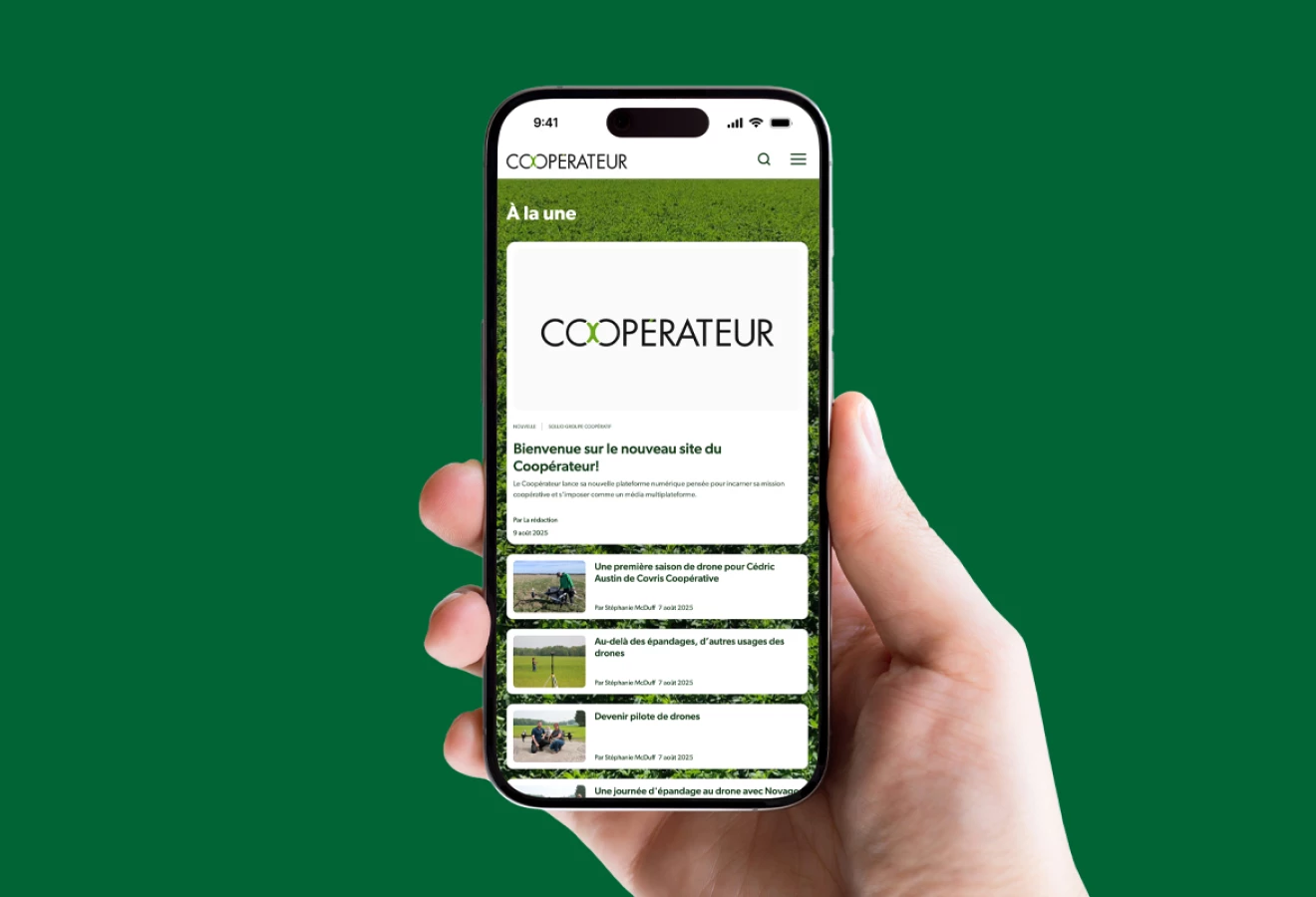 Une main tient un cellulaire sur lequel le site du Coopérateur apparaît