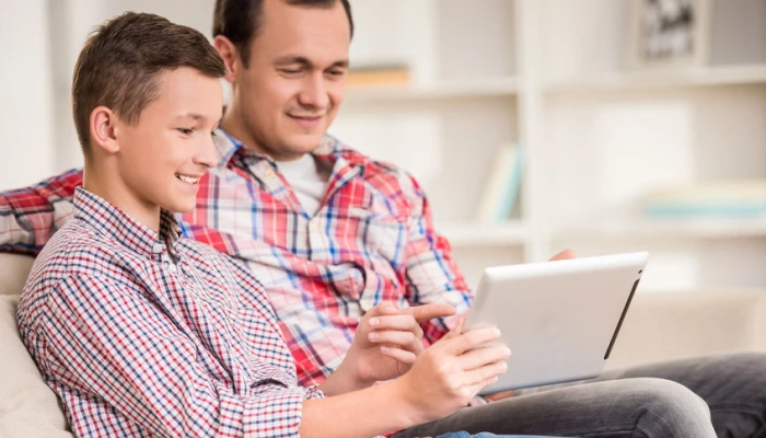 Photo d'un homme et son fils observant une tablette.