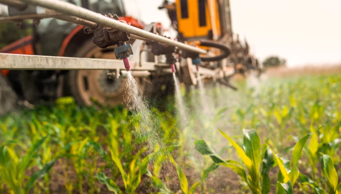 Tracteur en train d'arroser un champ de pesticides.