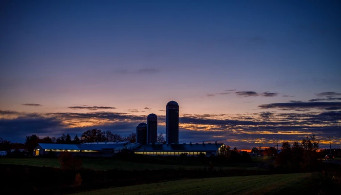 Vue de loin d'une ferme durant un coucher de soleil.