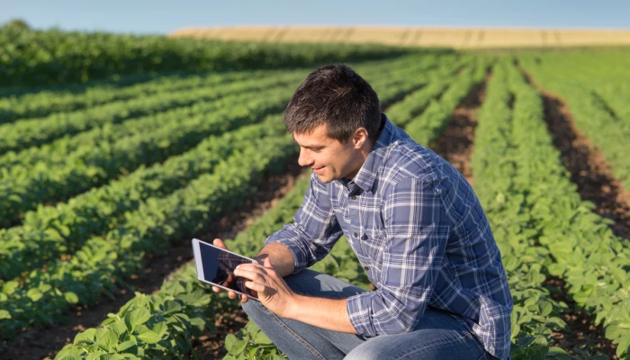 Homme souriant avec une tablette dans un champ