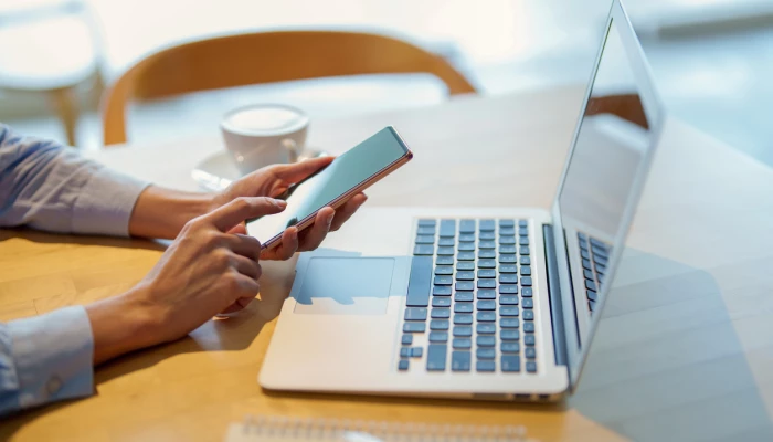 Personne utilisant son téléphone et son ordinateur.