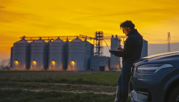 Homme utilisant une tablette devant des silos le matin