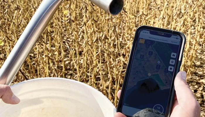Quelqu'un qui tient un sceau dans un champ en regardant son téléphone