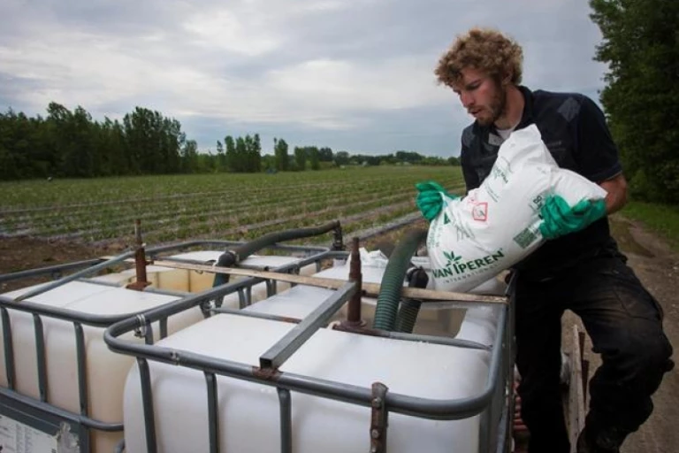 Homme en train de fertiliser son champ par la fertigation.