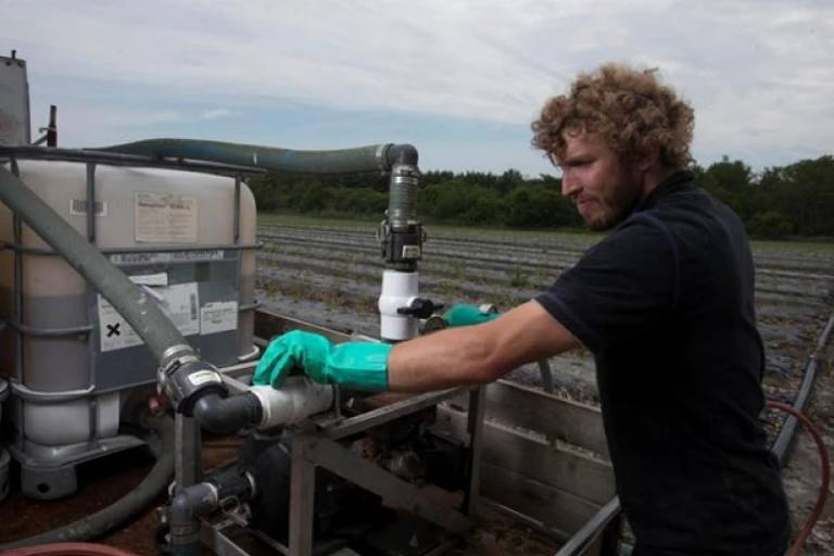 Homme s'assurant que les machines utilisés pour fertiliser son champ fonctionnent bien.